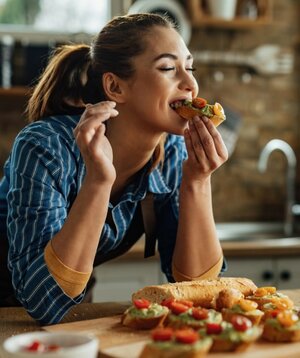 Eine Frau isst ein Sandwich in der Küche.