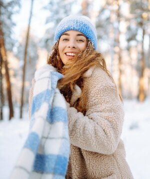 Eine junge Frau trägt einen blau-weissen Schaal in einer Winterlandschaft