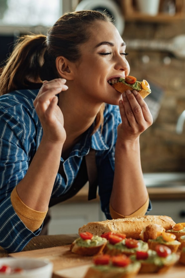 Eine Frau isst ein Sandwich in der Küche.