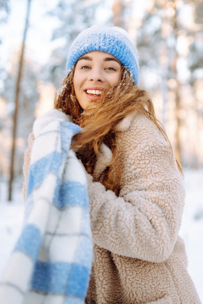 Eine junge Frau trägt einen blau-weissen Schaal in einer Winterlandschaft